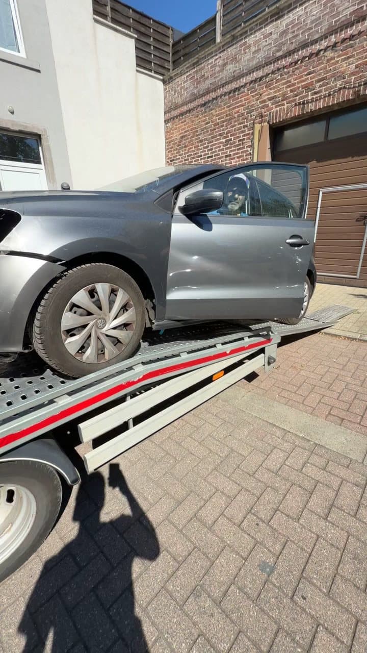 Une citadine grise portière ouverte, en train de monter sur le plateau