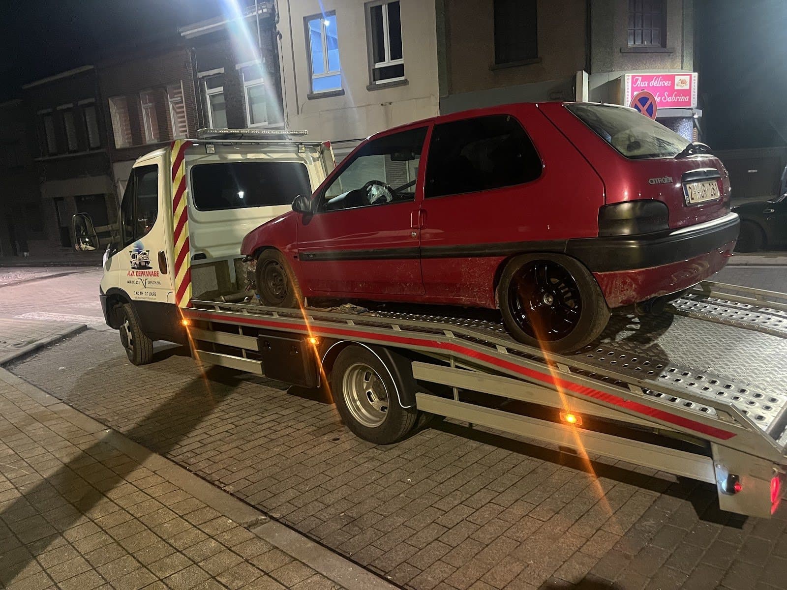 Une Citroën Saxo rouge chargée sur le plateau, de nuit