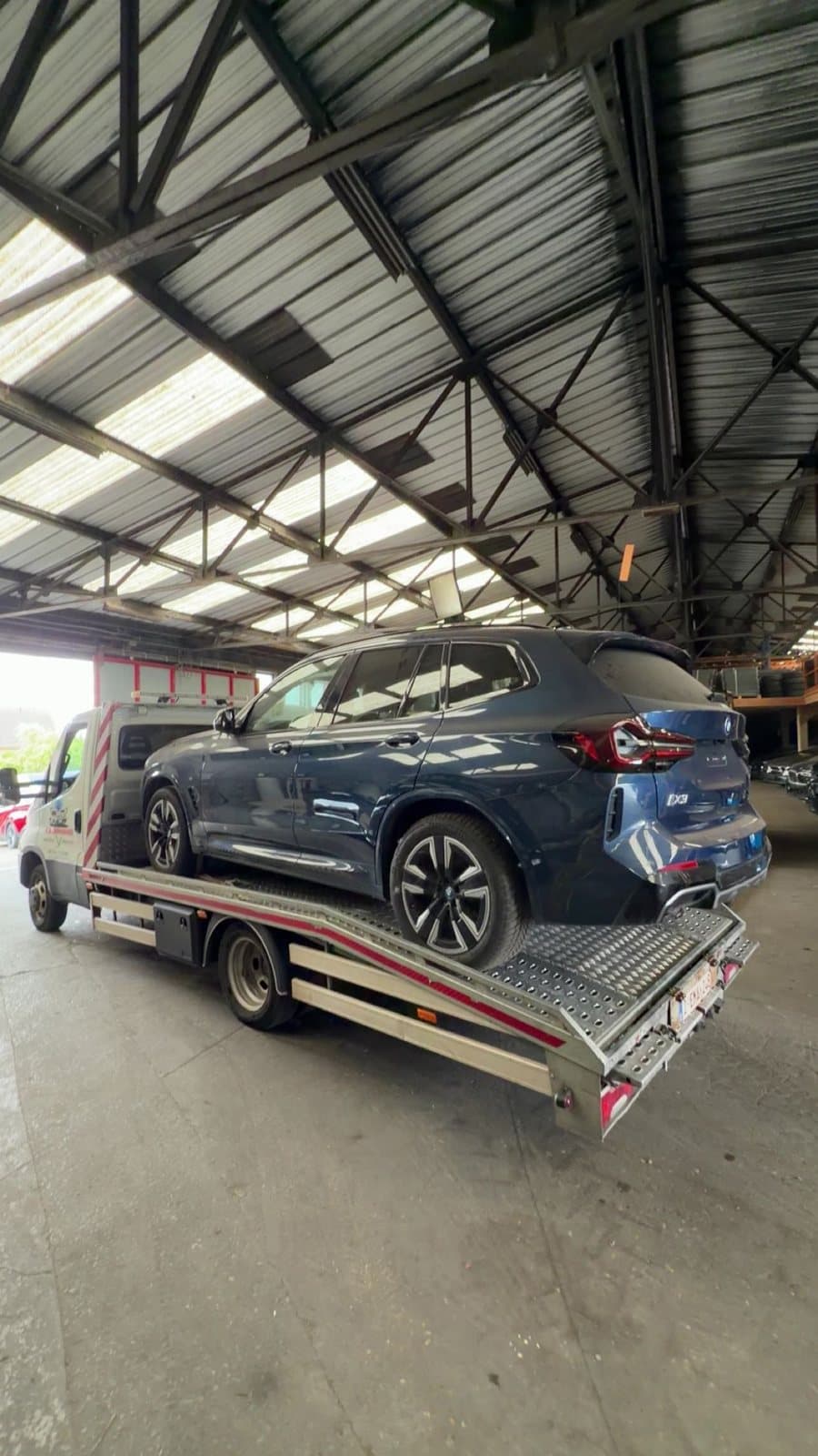 Un SUV bleu chargé sur le plateau, sous un hangar